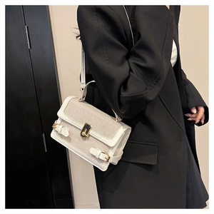 Detailed shot of white canvas crossbody bag with gold buckle on a black blazer jacket