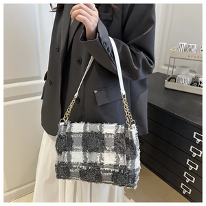 Detail of checkered tote bag featuring raw fringe edges and gold chain leather strap