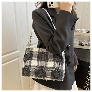 Detail of tweed check shoulder bag featuring fringe edges and gold chain strap