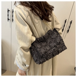 Detail of grey textured tweed crossbody bag with golden chain strap and fringe edges