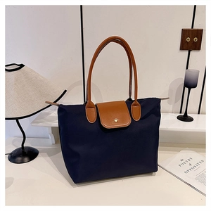 Gros plan sur le sac fourre-tout en nylon bleu avec poignées en cuir brun et bouton