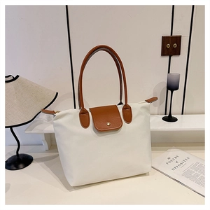 Détail du grand sac cabas en toile crème avec anses en cuir marron et fermeture éclair
