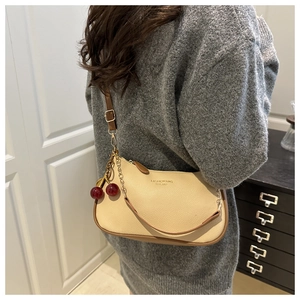 Detail of beige hobo bag with cherry pendant and adjustable brown shoulder strap