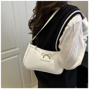 Detalle de bolso de axila en cuero PU blanco brillante con un lazo de metal dorado