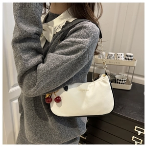 Détail du cuir grainé blanc et breloque cerise sur un sac à bandoulière
