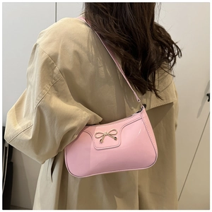 Detalle del bolso hobo de charol rosa con lazo de metal dorado en modelo con gabardina