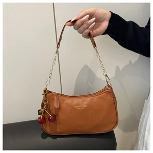 Detail of caramel lychee grain leather bag with gold chain and cherry charm