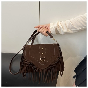 Detail of dark brown suede saddle bag with long fringe tassels and golden metal hardware