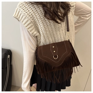 Detail of dark brown suede crossbody bag with bohemian fringes and gold D-ring hardware