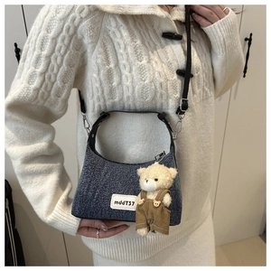 Vue détaillée du sac bandoulière en denim bleu avec un joli porte-clés ours en peluche