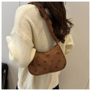 Detailed back view of a brown corduroy bag with small black bow prints on a shoulder strap