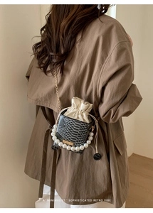 Detailed view of luxury snakeskin bucket bag with elegant pearl handle and gold chain