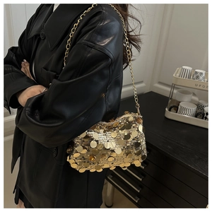 Detailed shot of golden sequin shoulder bag with chain strap on a black leather coat