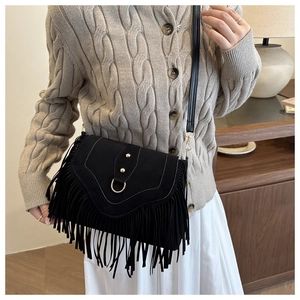 Détail du sac bandoulière en daim noir avec anneau en métal et franges sur modèle