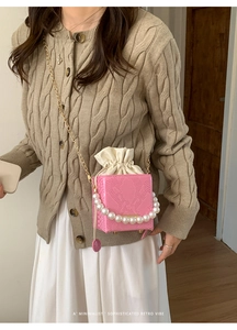 Macro shot of pink crocodile pattern leather bag with pearl handle and drawstring detail