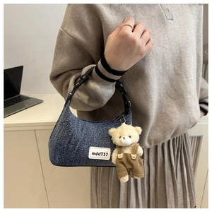 Détail d'un sac à épaule en jean bleu avec poignée en cuir et charm ours mignon