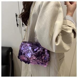Detail of purple sequin shoulder bag with golden chain strap on a trench coat