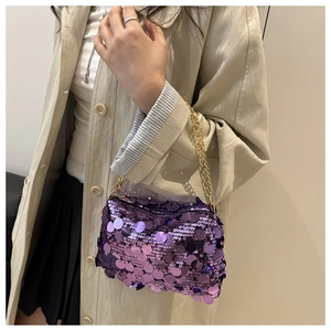 Detail of purple sequin evening bag with gold chain strap on a trench coat