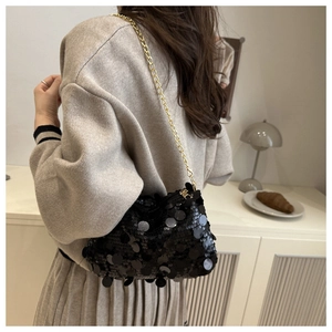 Détail du sac bandoulière à paillettes noires avec chaîne dorée porté à l'épaule