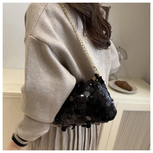 Détail d'un sac à paillettes noires avec chaîne dorée sur mannequin en tricot beige chiné