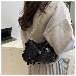 Détail du sac à bandoulière noir à paillettes avec chaîne dorée porté par un modèle