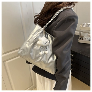 Detail of silver tote bag featuring woven straps and a cute cloud plush charm