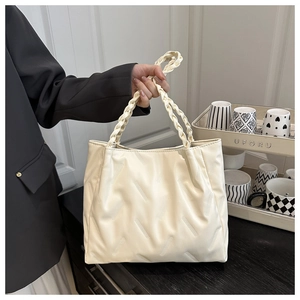 Close-up of cream white tote bag featuring unique diagonal pleated texture and woven handles