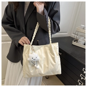 Detail of embossed diagonal patterns and woven strap on cream white large tote bag