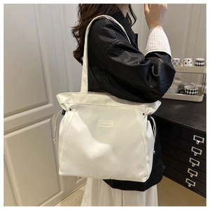 Close-up of white tote bag with black drawstring detail and Fashion text engraving