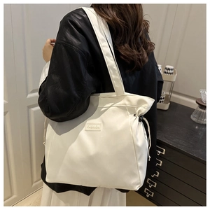 Close-up of white tote bag with FASHION lettering and adjustable drawstring detail