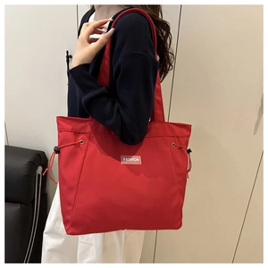Detailed view of red tote bag with fashion patch and adjustable side drawstrings