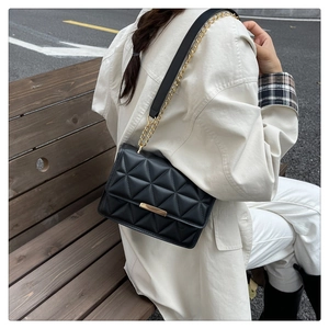 Detail of black quilted leather handbag with gold metal hardware and chain strap