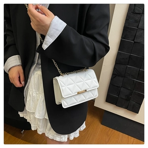 Macro detail of white quilted leather texture and golden metal bar buckle on flap bag