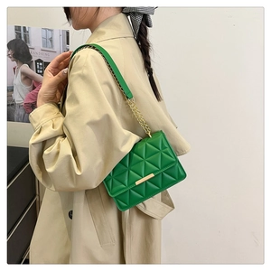Dettaglio borsa a tracolla verde trapuntata con catena dorata e chiusura metallica elegante