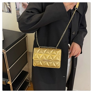 Dettaglio borsa a tracolla trapuntata dorata con catena e texture geometrica elegante