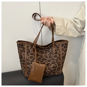 Detail of leopard print tote bag with brown leather handles and small zip pouch charm