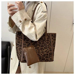 Detailed view of leopard print tote bag with brown leather straps and matching pouch