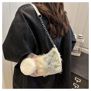 Detail of canvas underarm bag with star pattern, fringe edges and silver chain strap