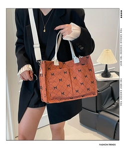 Close-up of orange corduroy tote bag with quilted diamond pattern and bow print