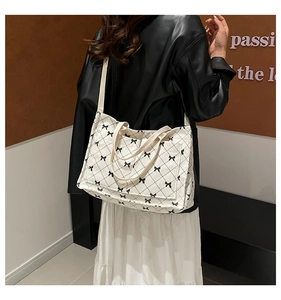 Detail of white corduroy tote bag with black bow and diamond pattern and long strap