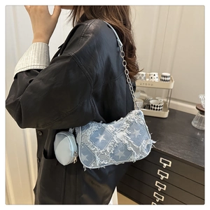 Detail of light blue denim shoulder bag with star pattern and frayed tassel edges