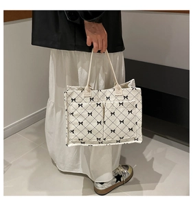 Detail of off-white corduroy tote bag with black bow patterns and front pockets