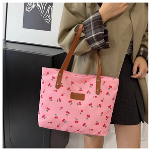 Detail of pink tote bag with red cherry print and brown leather shoulder straps