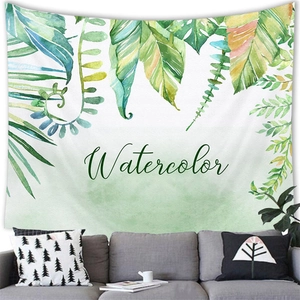 Detail of tropical monstera leaf tapestry with watercolor text hung over a gray sofa