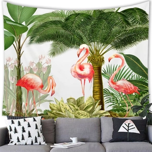 Tropical wall tapestry with pink flamingos and palm leaves hung over a grey sofa