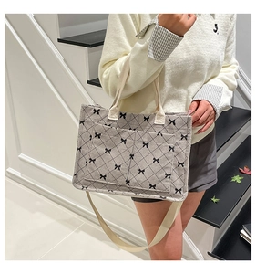 Detail of gray corduroy tote bag with quilted pattern and bow accent on white stairs