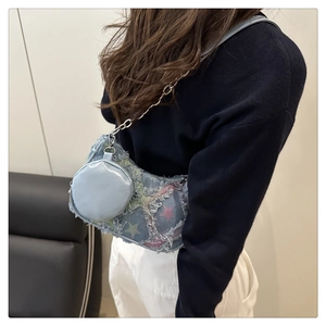 Detail of denim shoulder bag with colorful star prints and silver chain strap