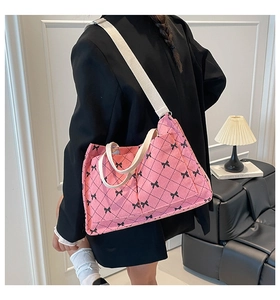 Detailed side view of pink corduroy quilted crossbody bag with black bow pattern