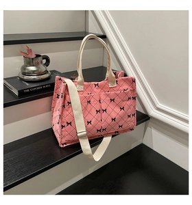 Detailed close-up of pink corduroy tote bag with bow prints and front pockets