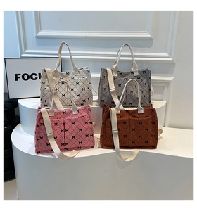 Detail of four quilted corduroy tote bags with black bows on a white geometric display